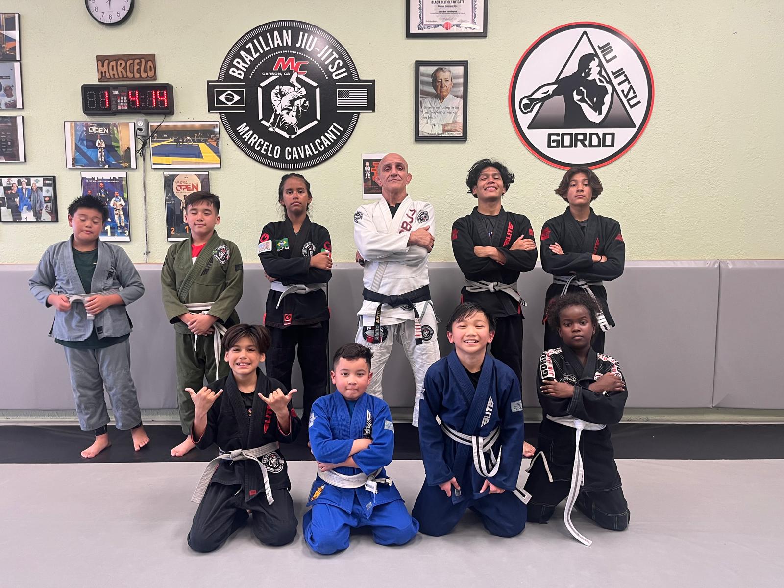 Kids BJJ class group photo at MCBJJ academy with MC logo on wall